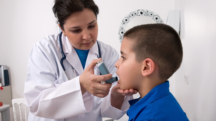 Female respiratory therapist treats male child patient using an aerosol medication.