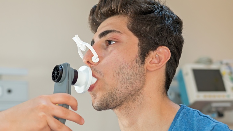 Male respiratory therapy patient taking pulmonary function test. 