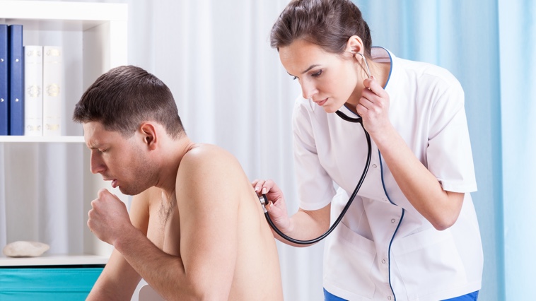 Female respiratory therapist uses a stethoscope to listen to a male patient's lungs. 