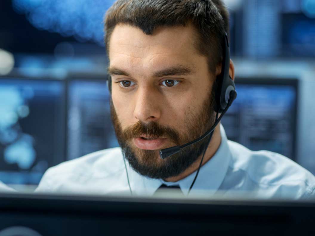 Male computer user support specialist on headset diagnosing a customer's computer problem. 