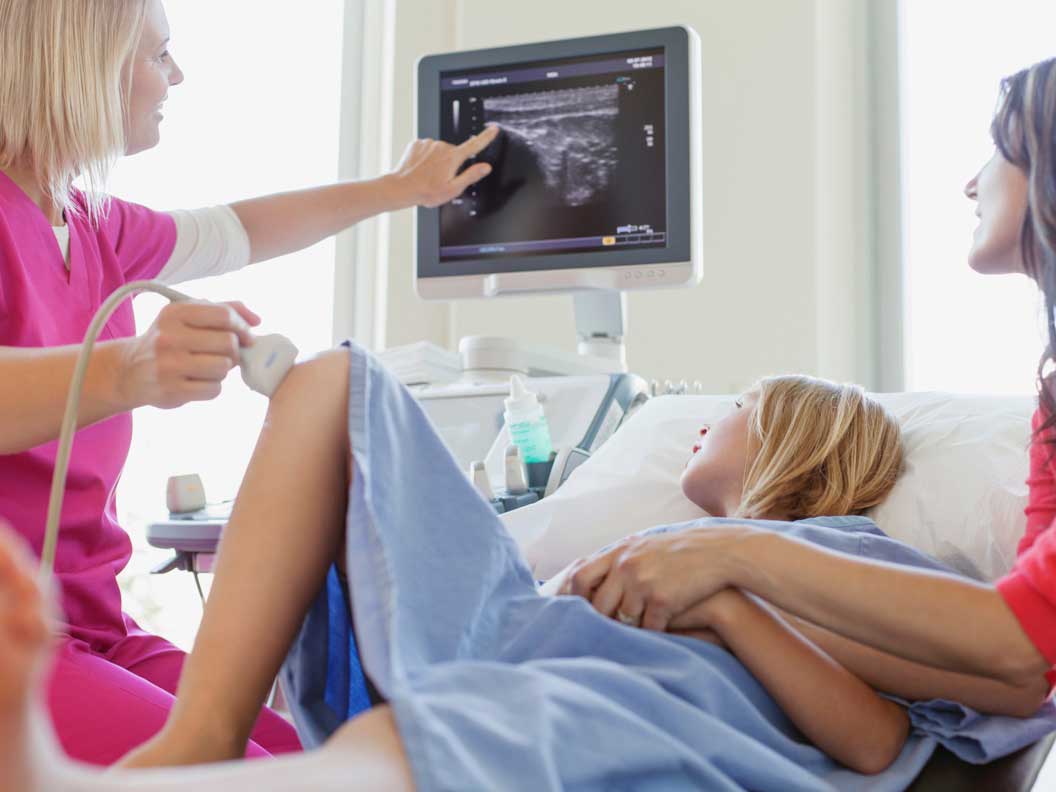 Female diagnostic medical sonographer reviews imaging results with female patients. 