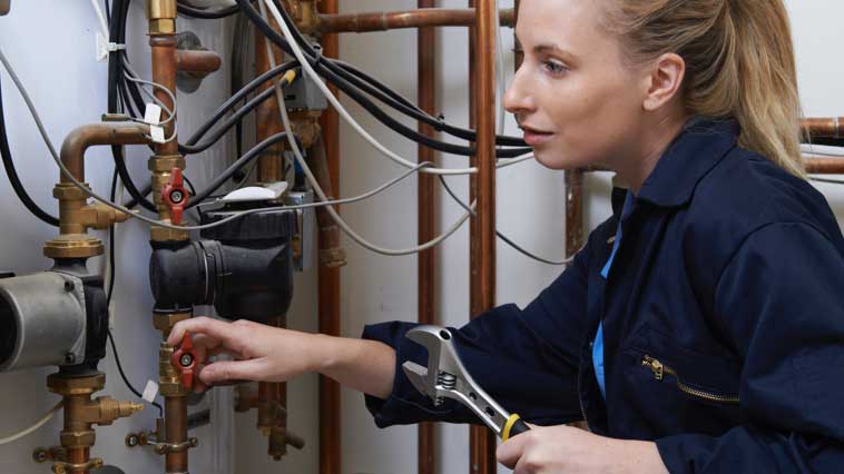 Female pipefitter troubleshoots a malfunctioning plumbing system. 