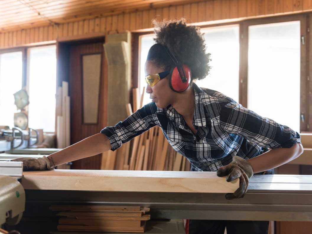 Female carpenter measures wood materials. 