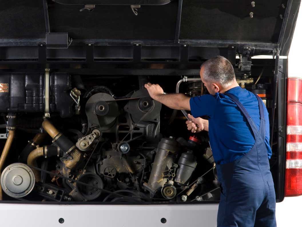 Male bus and truck mechanic performing an under the hood check. 