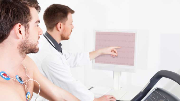 Male cardiovascular technician explains exercise stress test procedure to a male patient. 