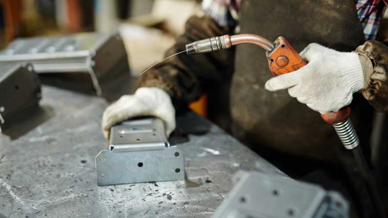 Welder examines welding equipment to maintain machinery. 